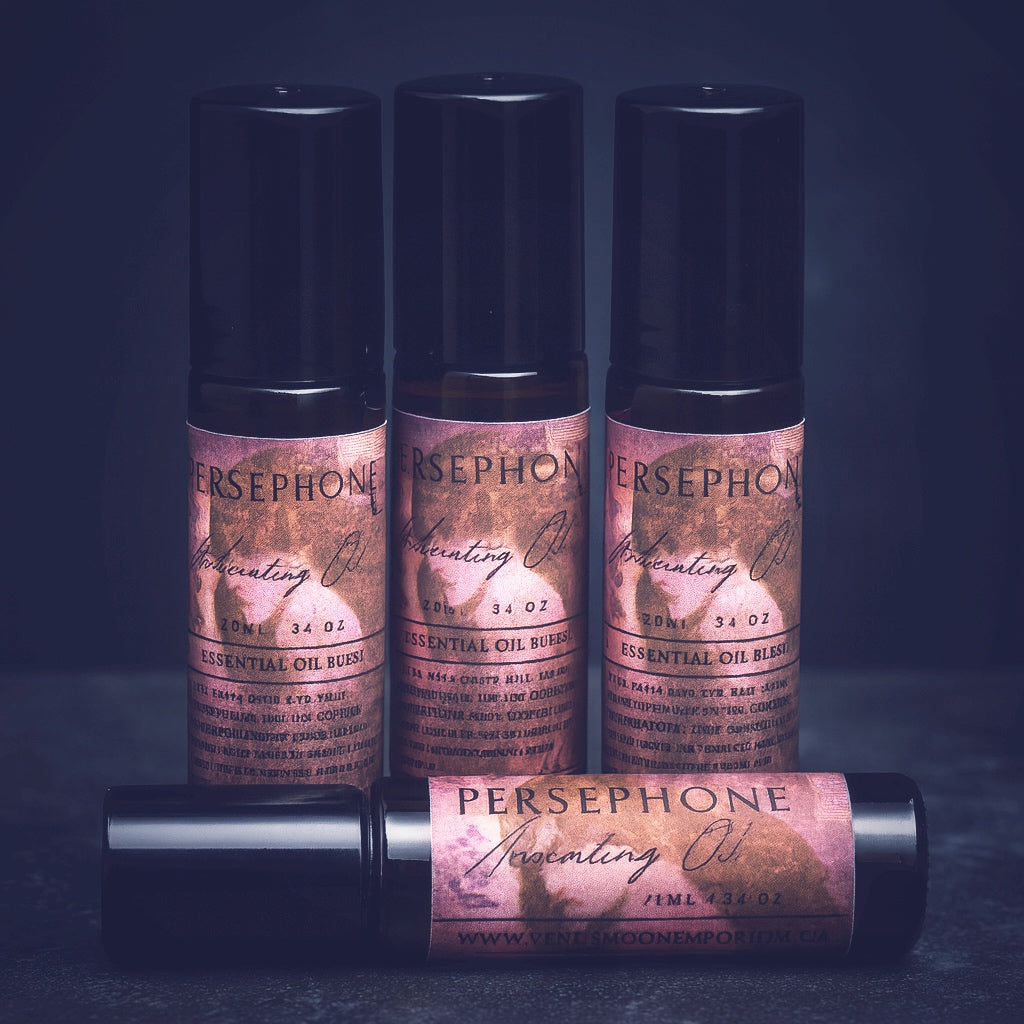 Dark, moody label for Persephone Anointing Oil from Venus Moon Emporium, featuring the Goddess against a deep red background with gold text. The 10ml black glass roller bottle rests in a witchy setting, crafted for ritual use and honoring Persephone’s descent and renewal.