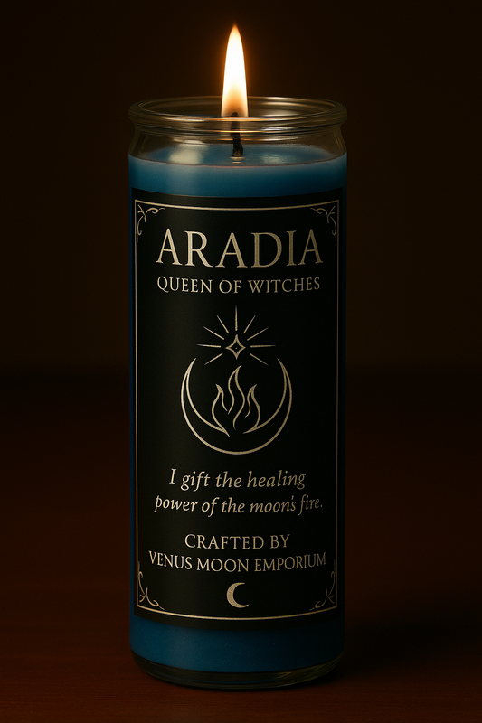 Lit 7-day blue devotional candle with black and silver Aradia label reading โQueen of Witches.โ The crescent moon and flame sigil glows in candlelight