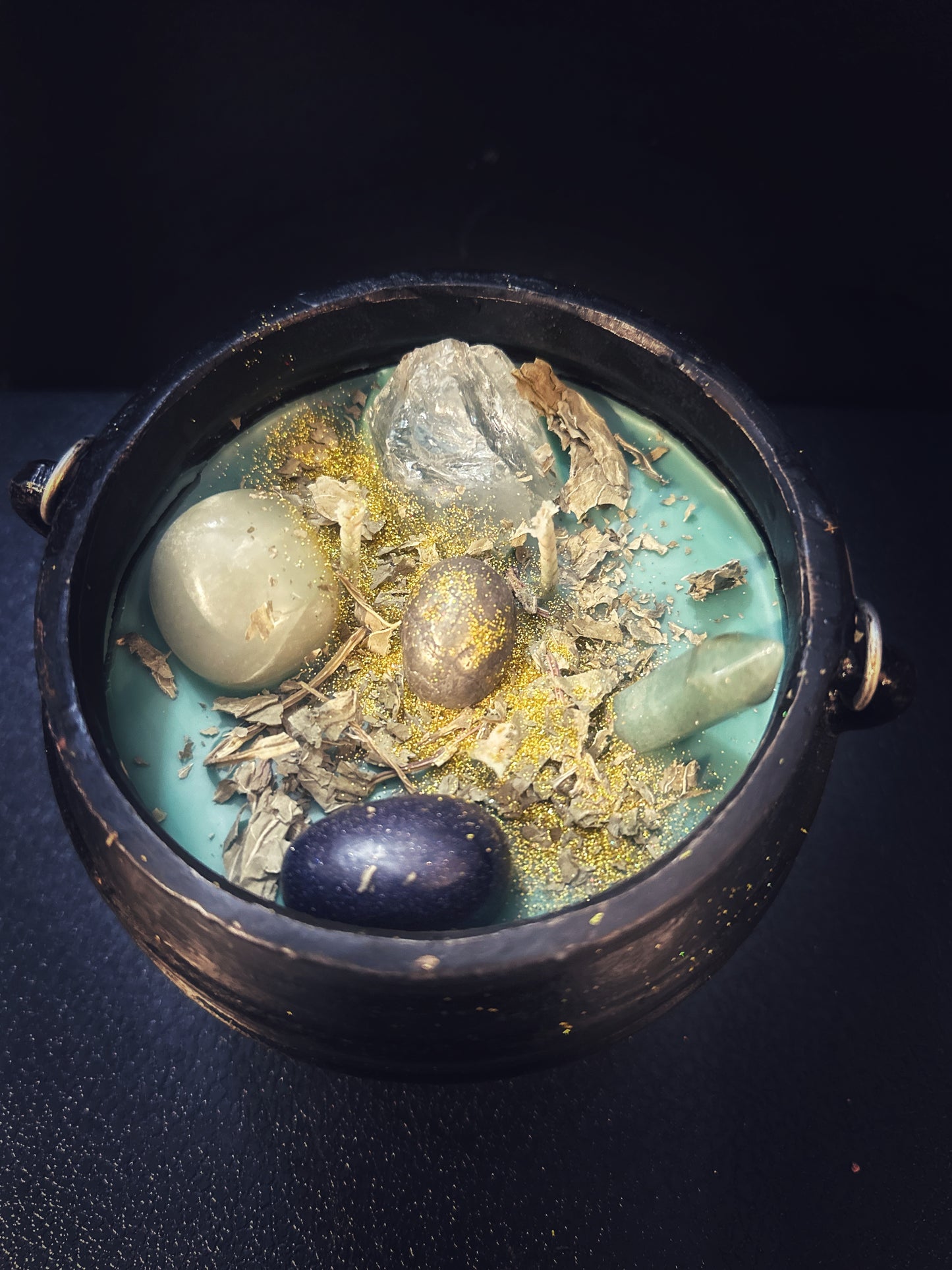 Green Fortuna Prosperity cauldron candle filled with herbs, crystals, and golden shimmer, hand-poured in cast iron for abundance rituals.