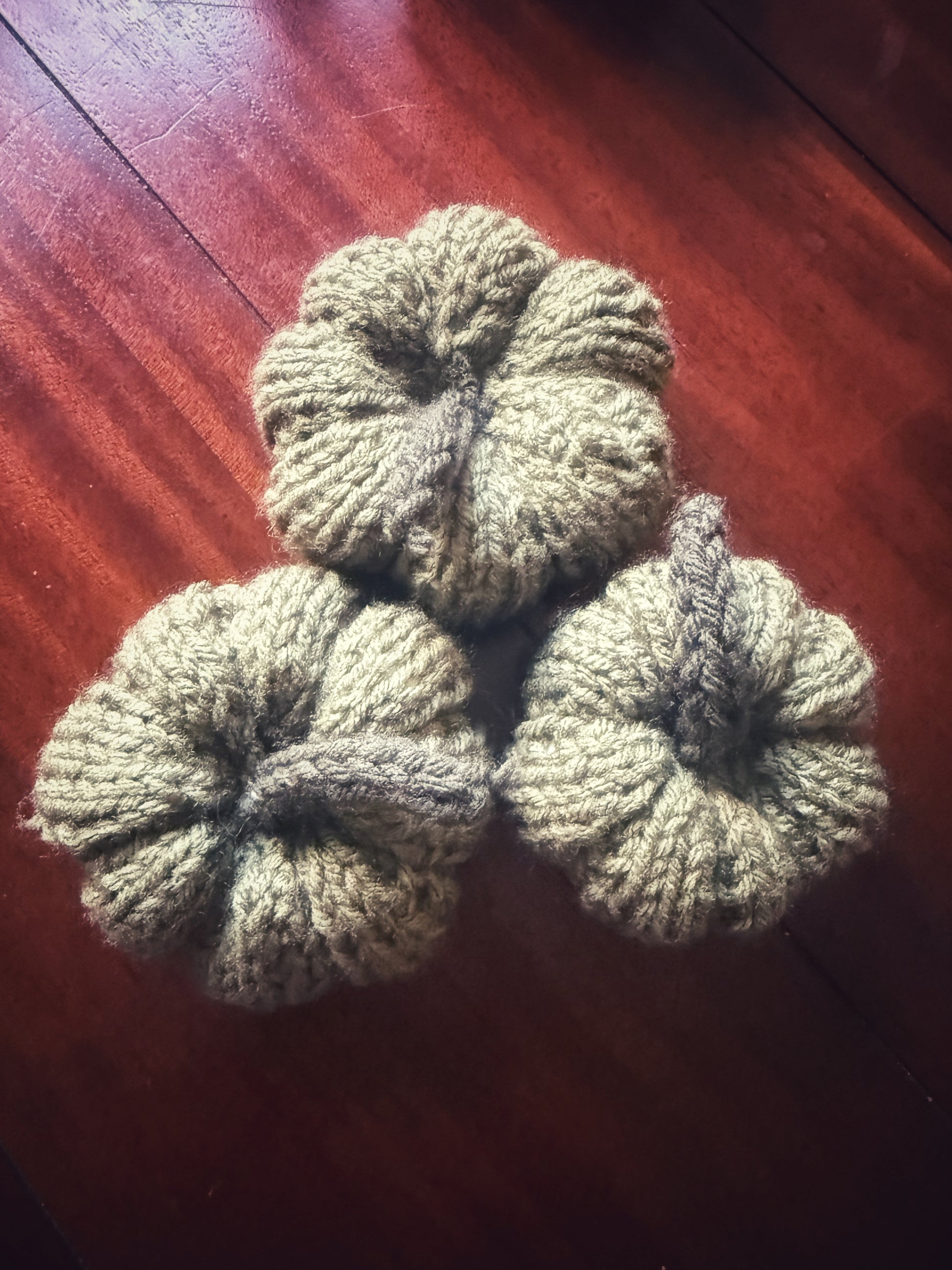 Hand-knit pumpkins in sage green, cozy fall décor pieces.