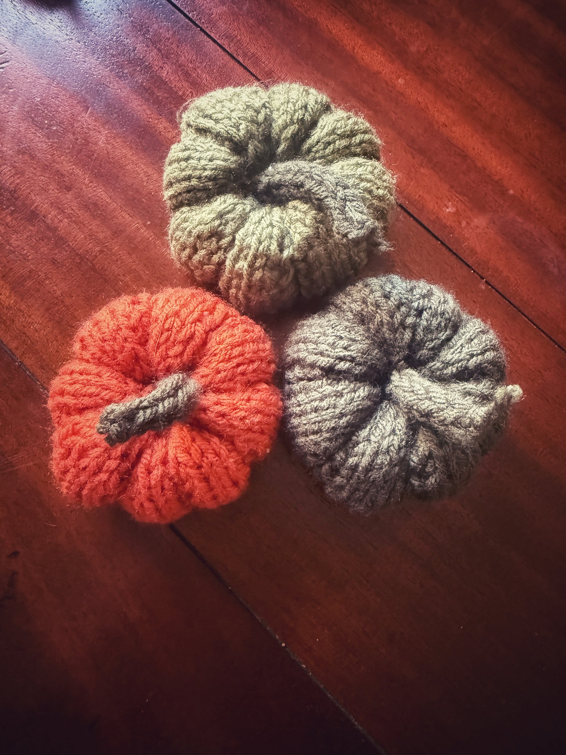 Set of handmade knit pumpkins in green and orange, cozy autumn table styling.