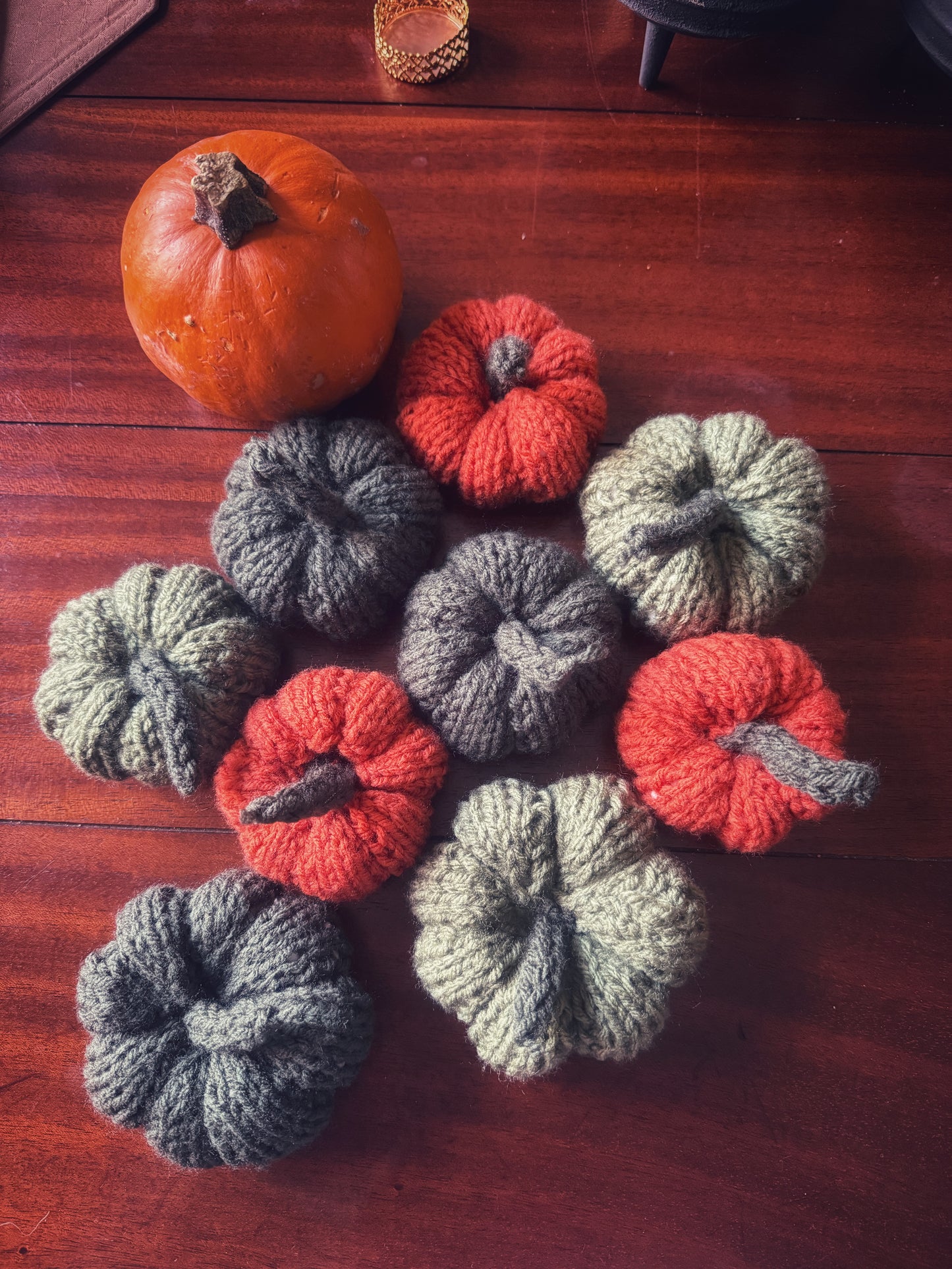 A harvest gathering of hand-knit pumpkins in earthy greens and vibrant orange, bringing autumn magic indoors.