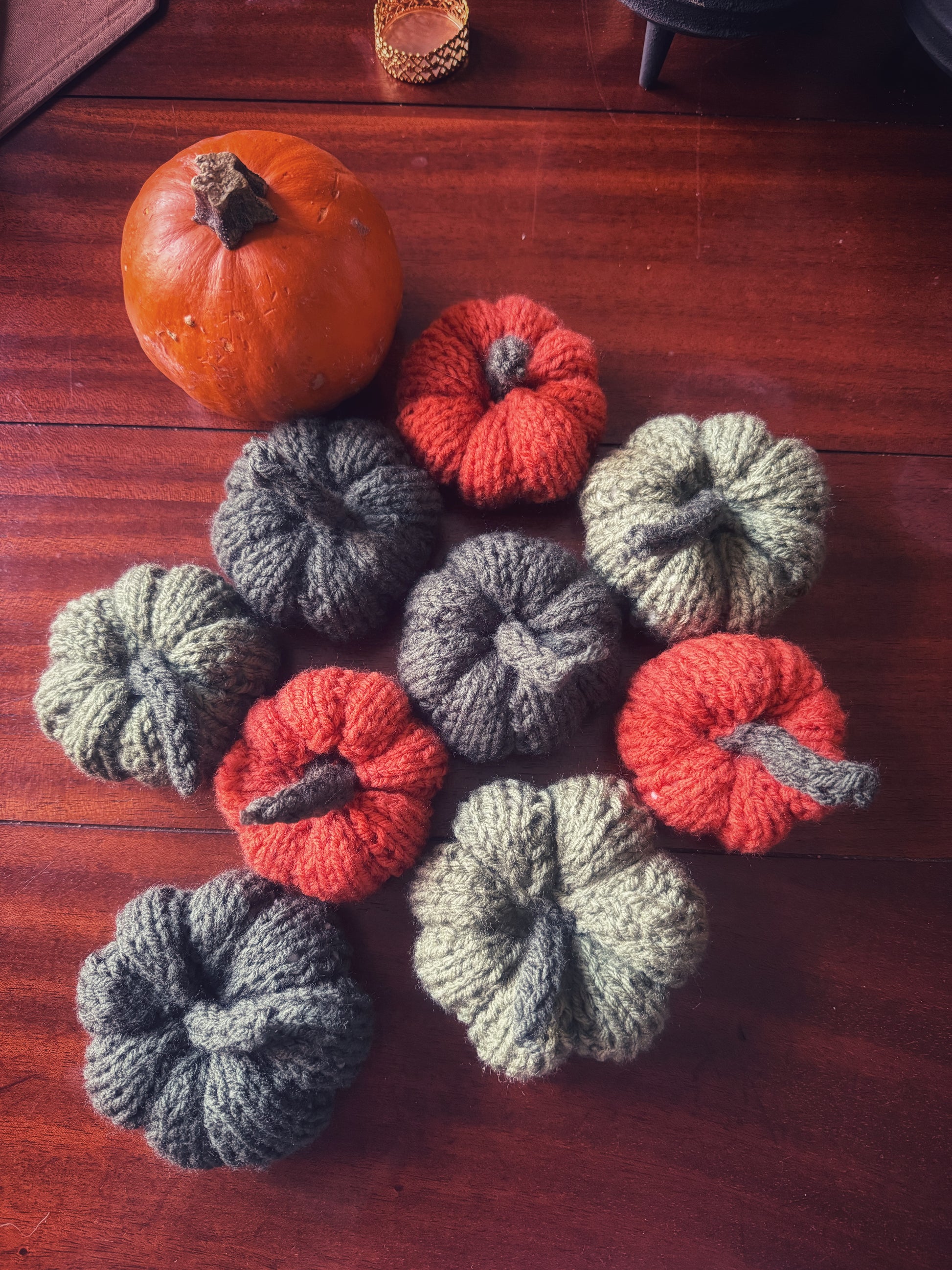 A harvest gathering of hand-knit pumpkins in earthy greens and vibrant orange, bringing autumn magic indoors.
