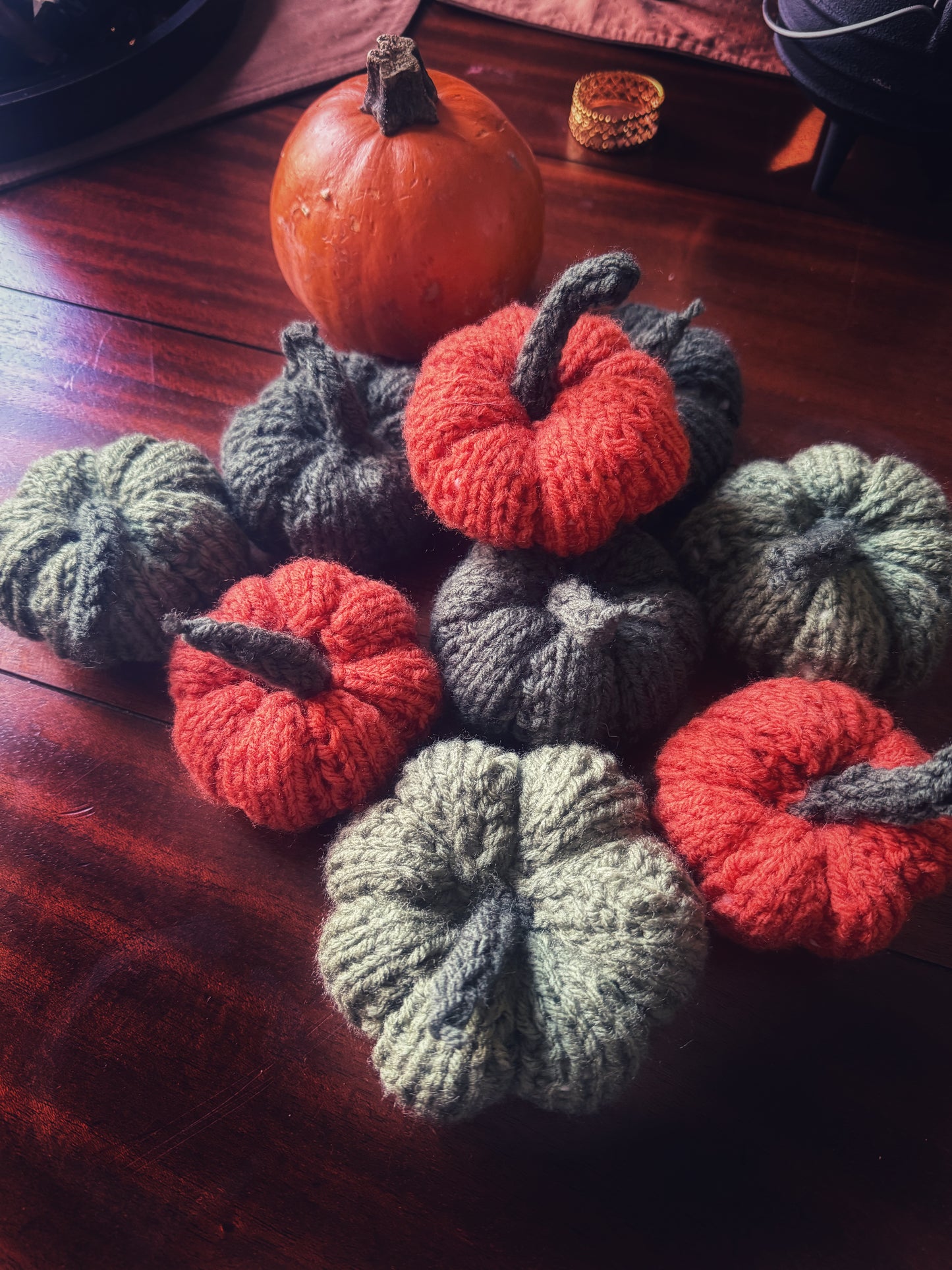 Set of handmade knit pumpkins in green and orange, cozy autumn table styling.