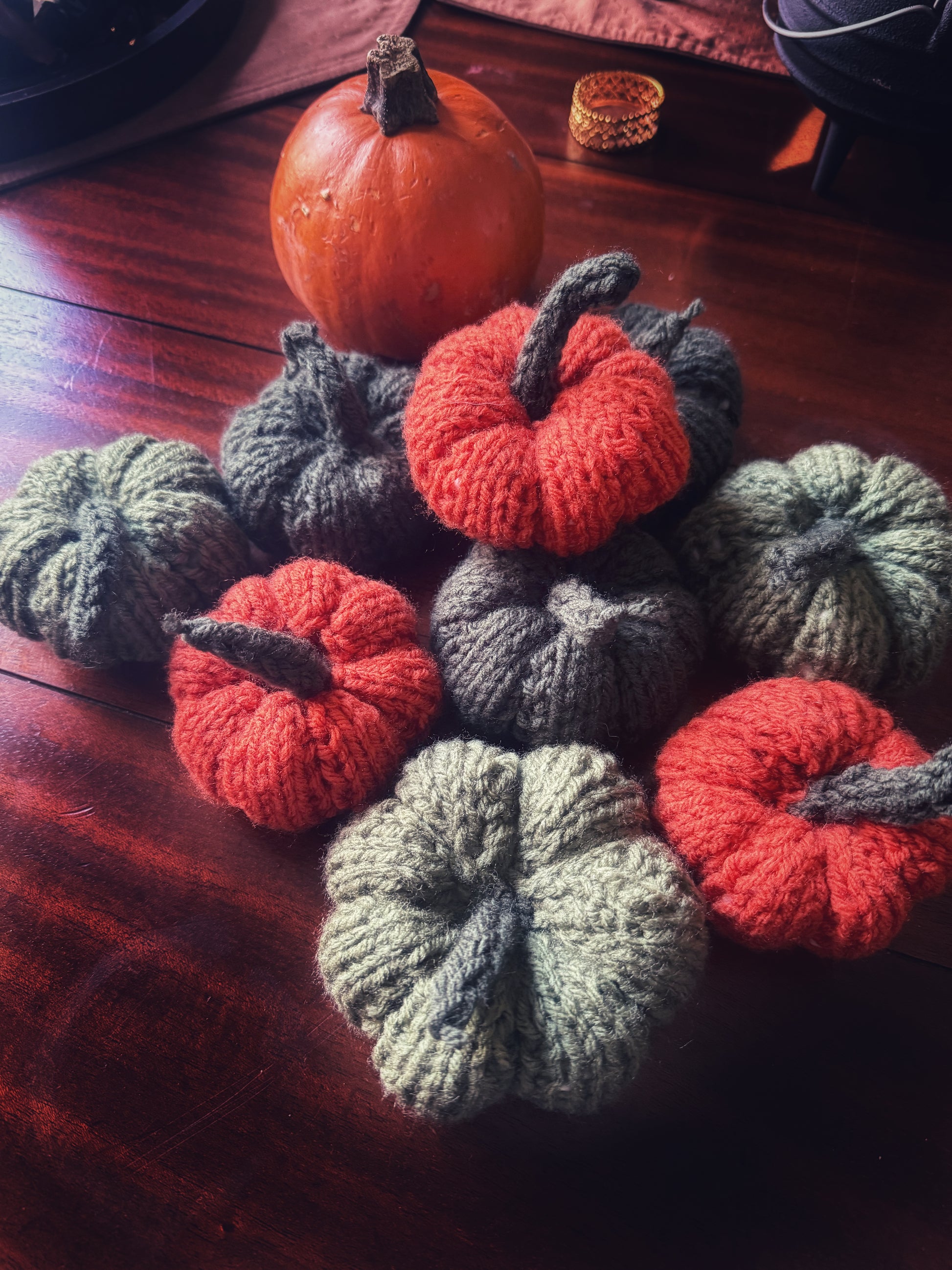 Set of handmade knit pumpkins in green and orange, cozy autumn table styling.